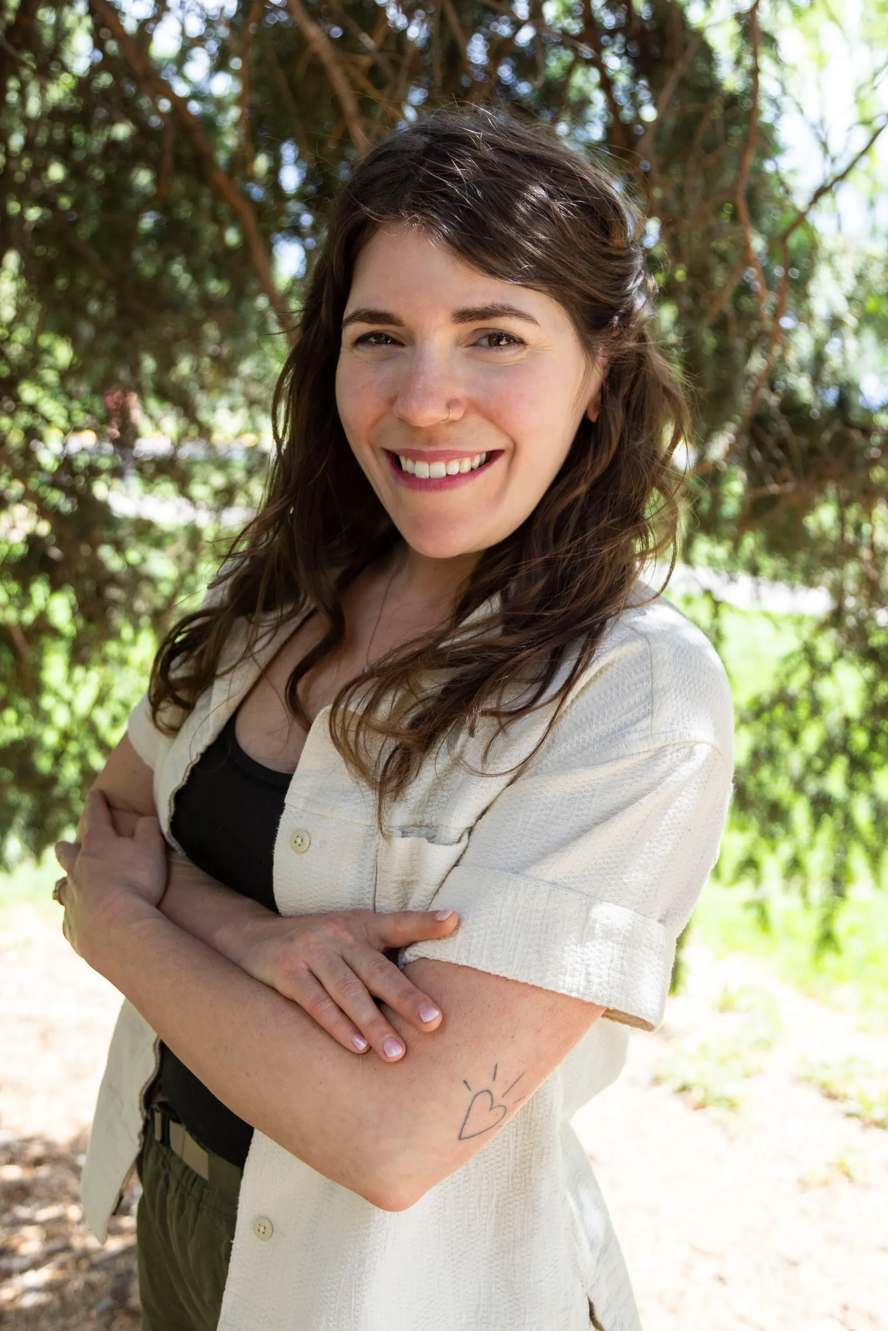 Portrait of Gina, smiling outdoors beneath a tree