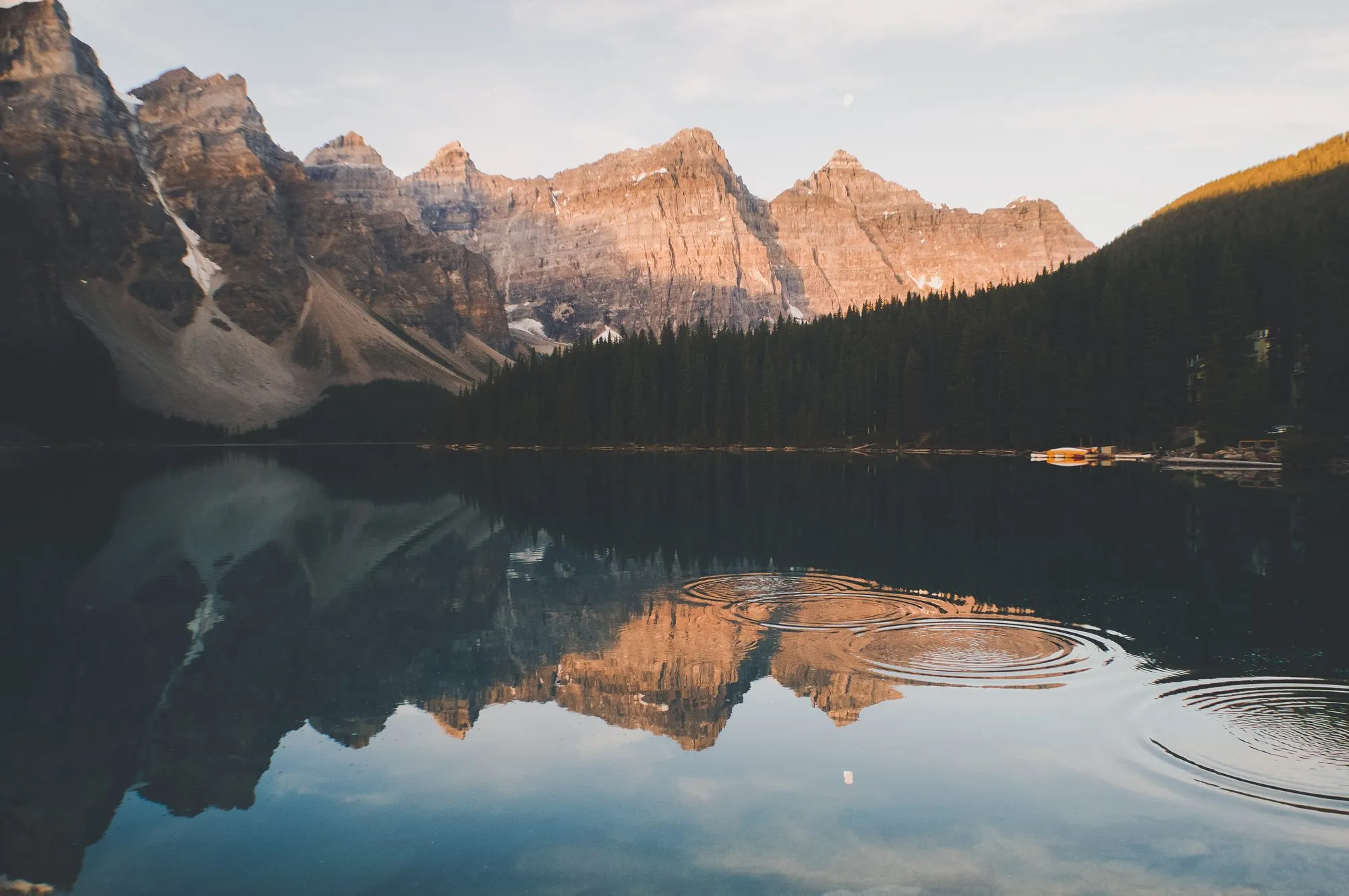 Rings spreading across the still surface of a mountain lake at dawn